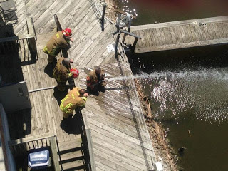 An overhead picture of firefighters spraying a firehose off a deck