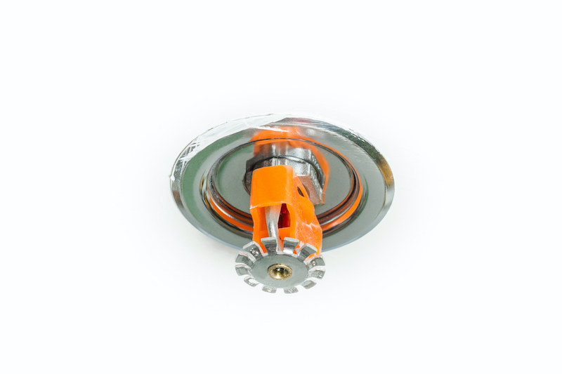 Close up image of fire sprinkler on white. Fire sprinklers are part of an integrated water piping system