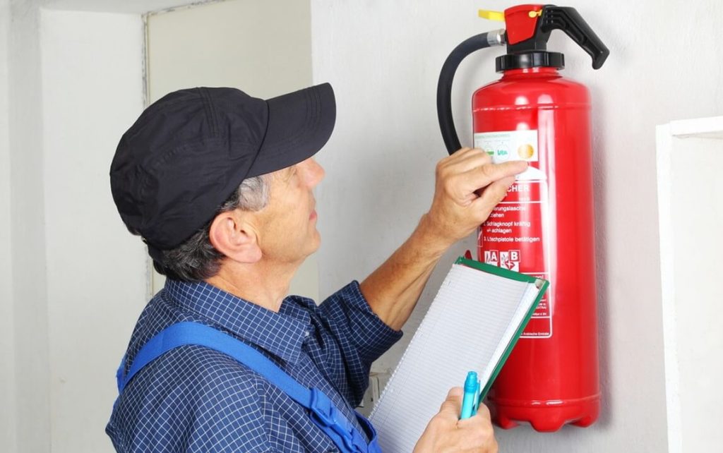 man inspecting fire extinguisher expiry date