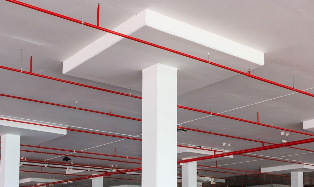 Fire sprinkler system with red water pipes along a white ceiling