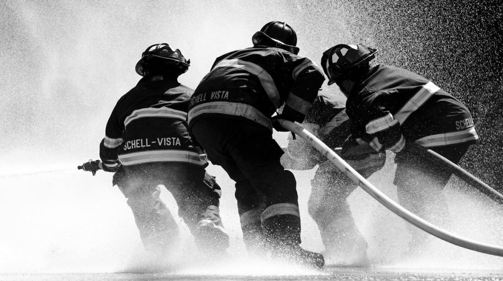 Black and white photo of firefighters putting out a fire